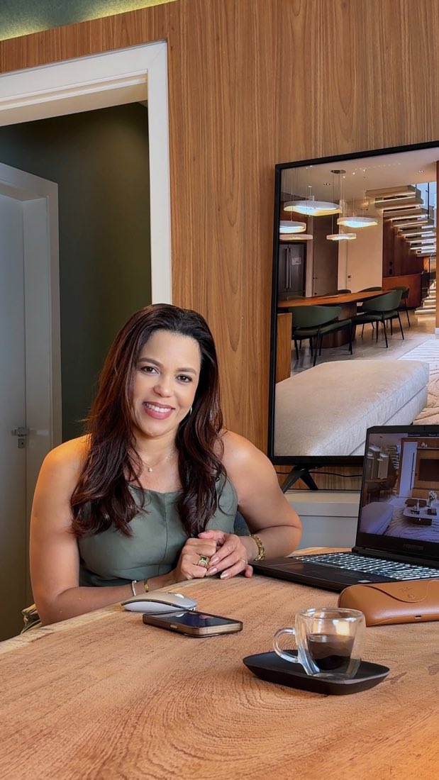 Designer sentada à mesa de madeira com notebook e xícara de café, vídeo sobre projeto 3D da Ana Paula Lima Interiores
