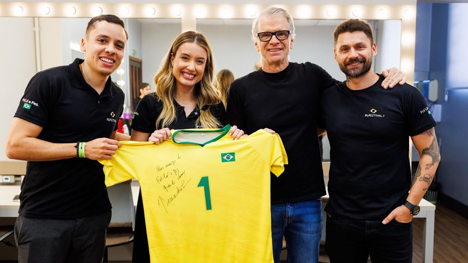 Quatro pessoas segurando uma camisa amarela autografada com o número 1, capa do vídeo sobre o FLFeztival 2025 do canal de Danilo Azambuja