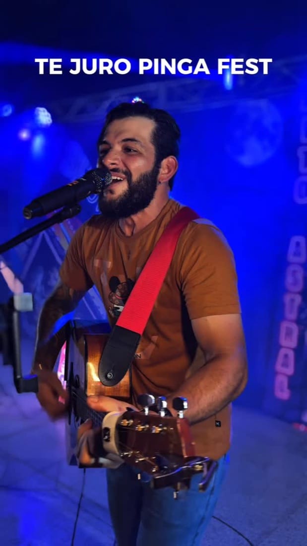 Cantor com violão no palco sob luz azul, vídeo do show de Felipe Fiel
